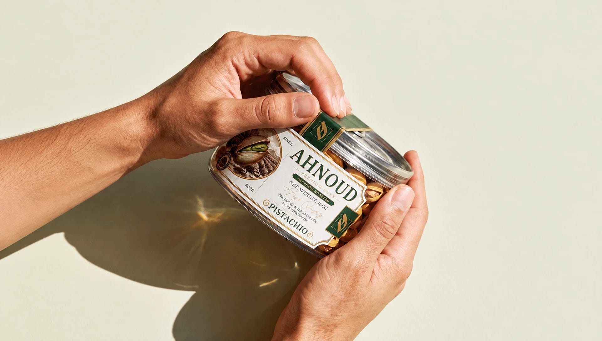 Two hands opening an Ahnoud pistachio can in sunlight